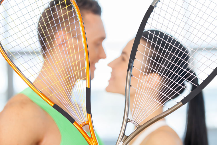Fitness couple. Loving couple kissing behind tennis racket